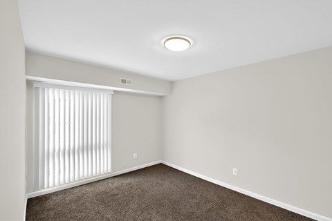 an empty living room with a large window and blinds